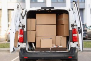 A family sealing cardboard boxes and sorting household items in a living room filled with packed belongings.