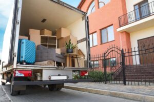 People organize labeled boxes while wrapping dishes and folding clothing in a bright home.